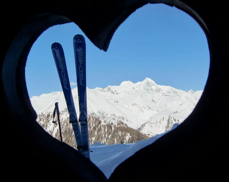 Ski vor verschneiten Bergen, durch ein Herz fotografiert